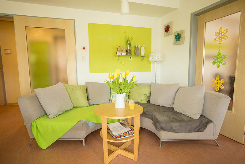 Wohnzimmer mit rundem Sofa und grünen Details