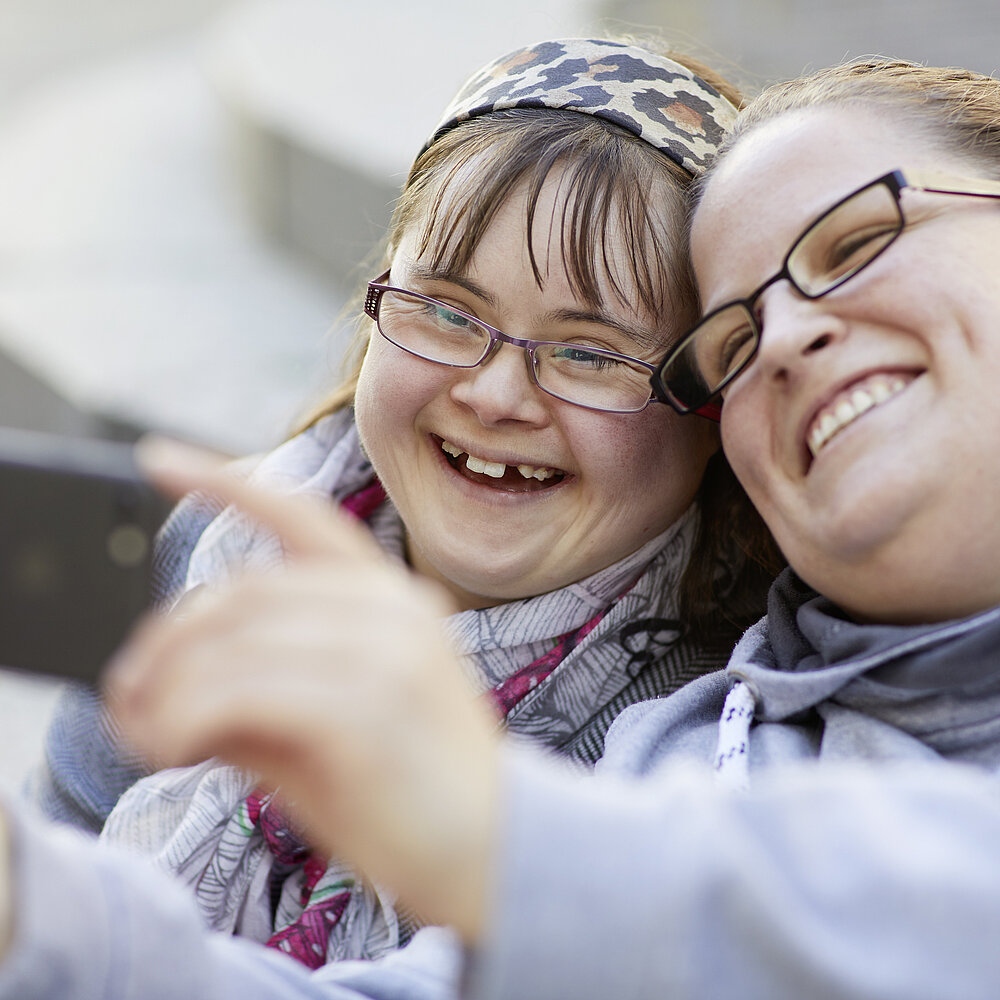 zwei Menschen lachen und machen ein Selfie